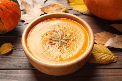 Photo of Bowl with tasty pumpkin soup on wooden table