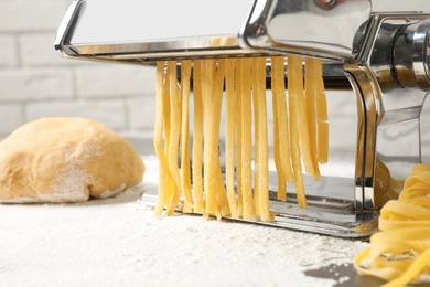 Photo of Pasta maker with dough on kitchen table