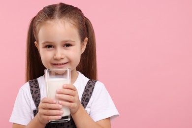 Cute girl with glass of fresh milk on pink background, space for text