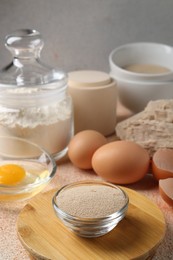 Photo of Compressed and dry granulated yeast, flour and eggs on orange textured table