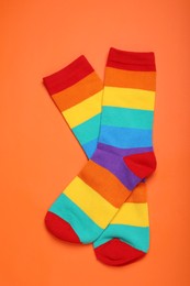 Photo of Rainbow socks on orange background, flat lay. LGBT pride