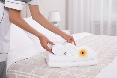 Photo of Chambermaid putting flower with fresh towels in hotel room, closeup