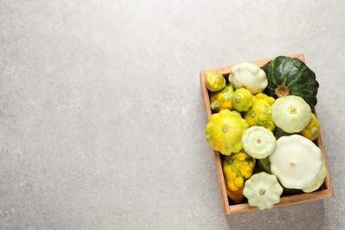 Photo of Fresh ripe pattypan squashes in wooden crate on light grey table, top view. Space for text