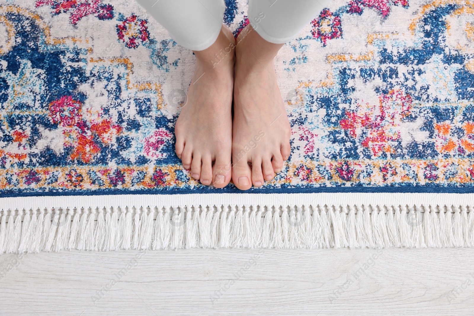 Photo of Woman standing on carpet with pattern at home, top view