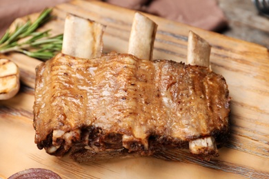 Photo of Roasted ribs on wooden board, closeup. Tasty meat
