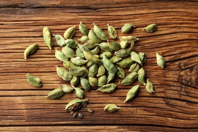 Pile of dry cardamom pods on wooden table, top view