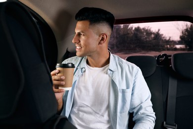 Photo of Man with cup of drink in modern taxi
