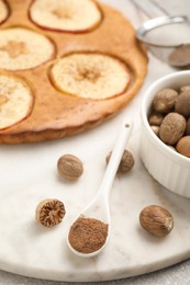 Nutmeg powder, seeds and tasty apple pie on table