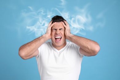 Stressed and upset young man on light blue background