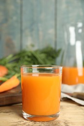 Photo of Glass of freshly made carrot juice on wooden table