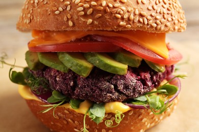 Photo of Tasty vegetarian burger with beet cutlet, cheese, avocado and tomato on table, closeup