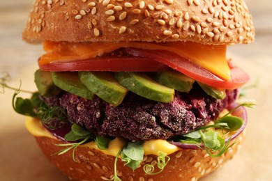 Tasty vegetarian burger with beet cutlet, cheese, avocado and tomato on table, closeup