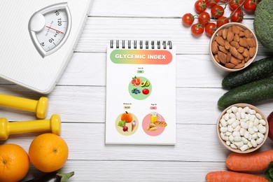 Information about grouping of products under their glycemic index. Notebook, almonds, beans, fruits, vegetables, dumbbells and floor scale on white wooden table, flat lay