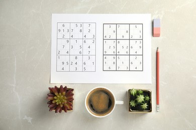 Photo of Sudoku, pencil, eraser, cup of coffee and houseplants on light grey table, flat lay