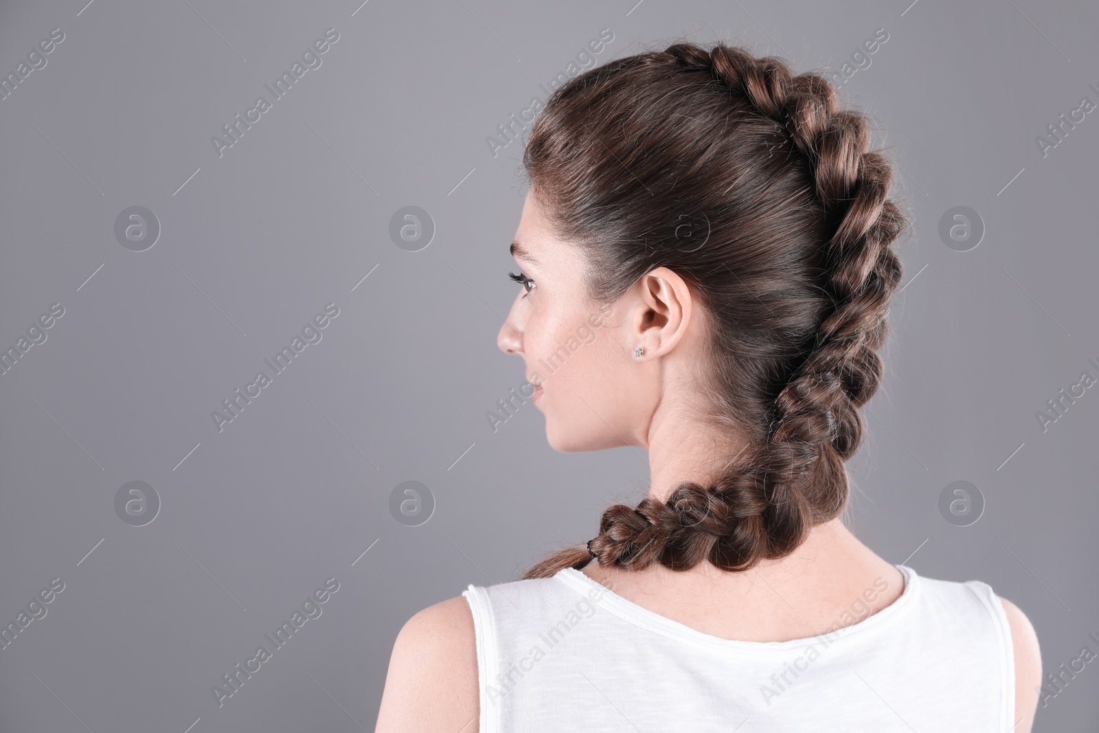 Photo of Woman with braided hair on grey background, back view. Space for text