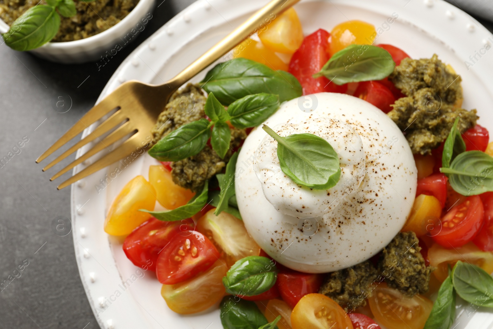 Photo of Delicious burrata salad served on grey table, closeup