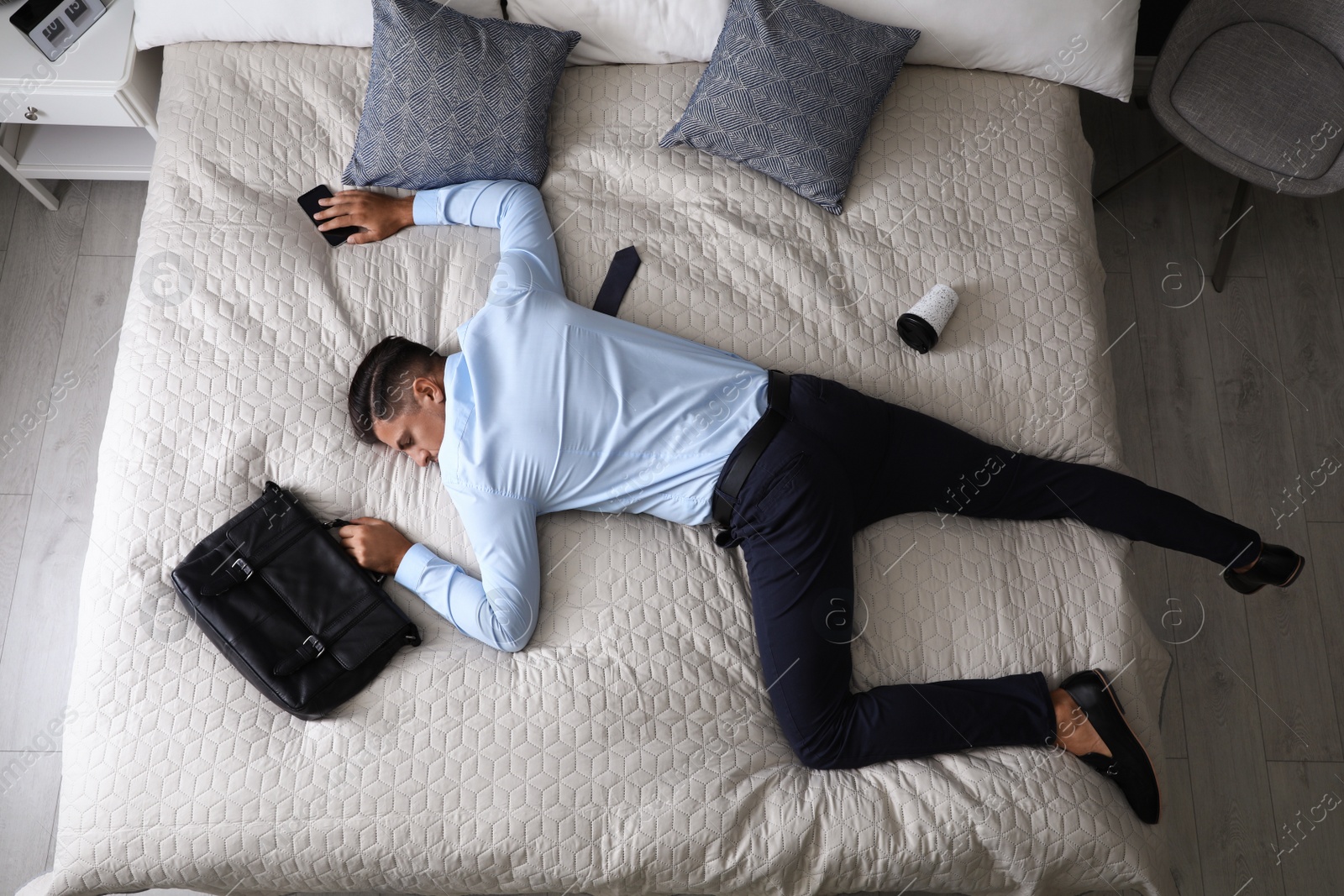 Photo of Exhausted businessman in office wear sleeping on bed at home after work, above view