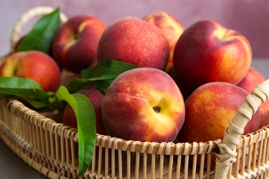 Photo of Wicker tray with juicy peaches on table, closeup