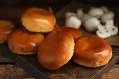 Delicious baked mushrooms pirozhki on wooden board, closeup