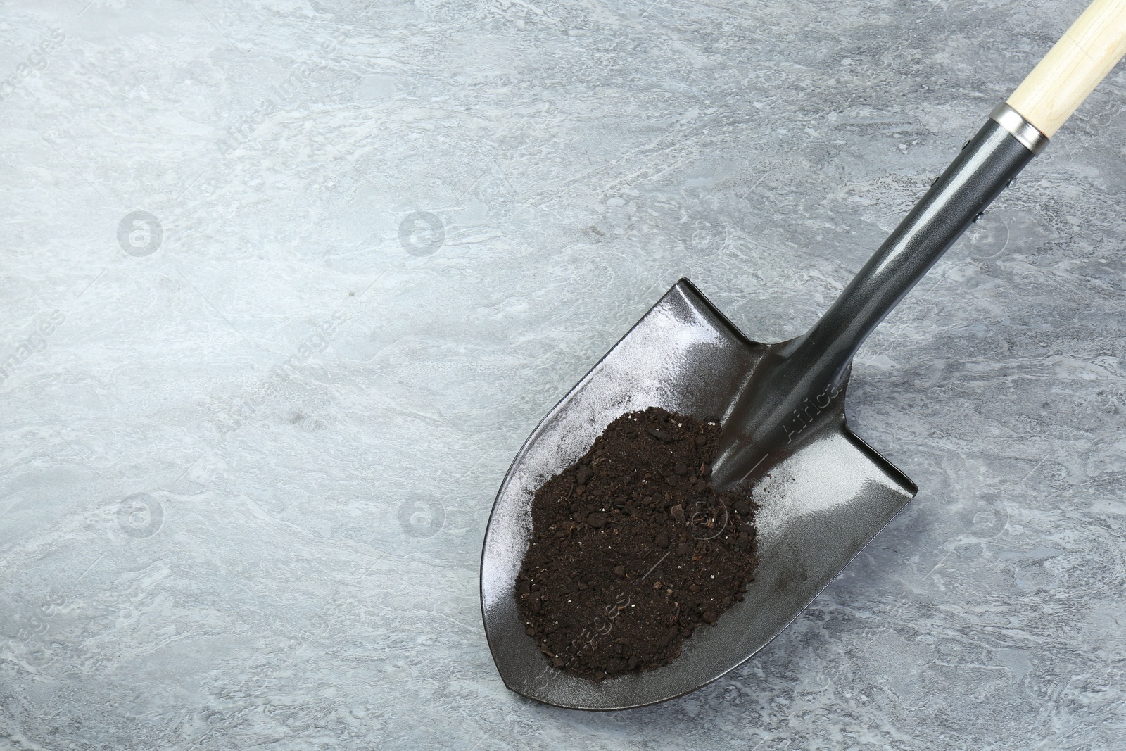 Metal shovel with fertile soil on gray background, above view. Space for text Photo of Metal shovel with fertile soil on gray background, above view. Space for text