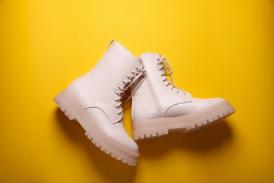 Pair of stylish leather shoes on yellow background, flat lay