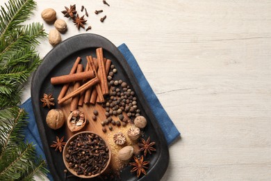 Photo of Different spices, nuts and fir branches on wooden table, flat lay. Space for text
