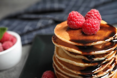 Delicious pancakes with fresh raspberries and chocolate syrup on table, closeup