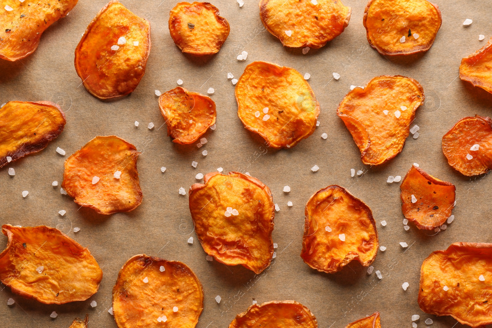 Photo of Sweet potato chips with salt on color background, flat lay