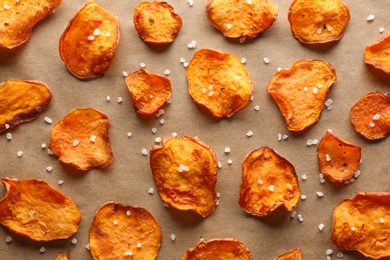 Sweet potato chips with salt on color background, flat lay