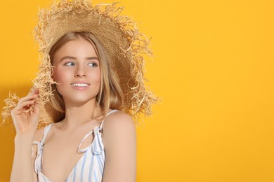 Photo of Beautiful young woman in straw hat on orange background, space for text