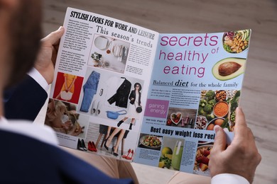 Man reading paper magazine indoors, closeup view