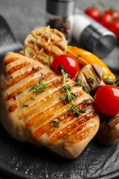 Photo of Tasty grilled chicken fillet with tomatoes and thyme on board, closeup