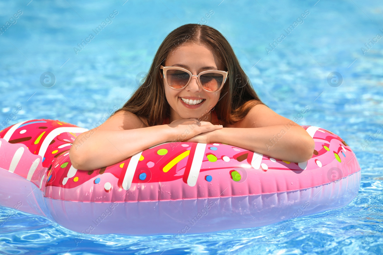 Photo of Beautiful young woman on inflatable ring in swimming pool