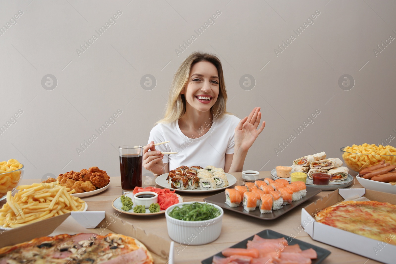 Photo of Blogger with lots of food at table against beige background. Mukbang vlog