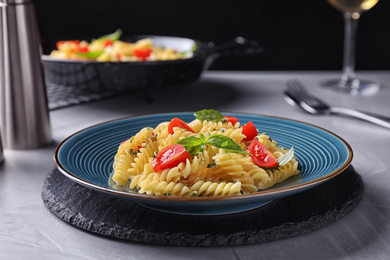 Delicious pasta with tomatoes and basil served on grey table