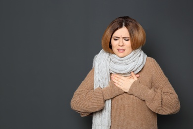 Photo of Woman suffering from cough on dark background. Space for text