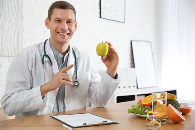 Photo of Nutritionist with apple at desk in office