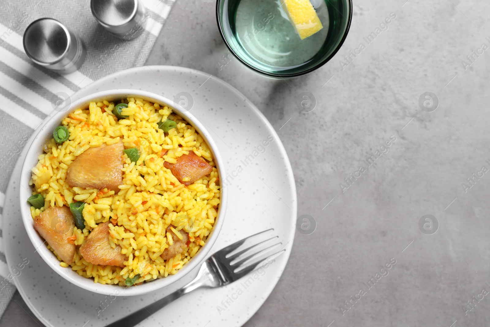 Photo of Delicious pilaf with chicken meat served on light grey table, flat lay. Space for text