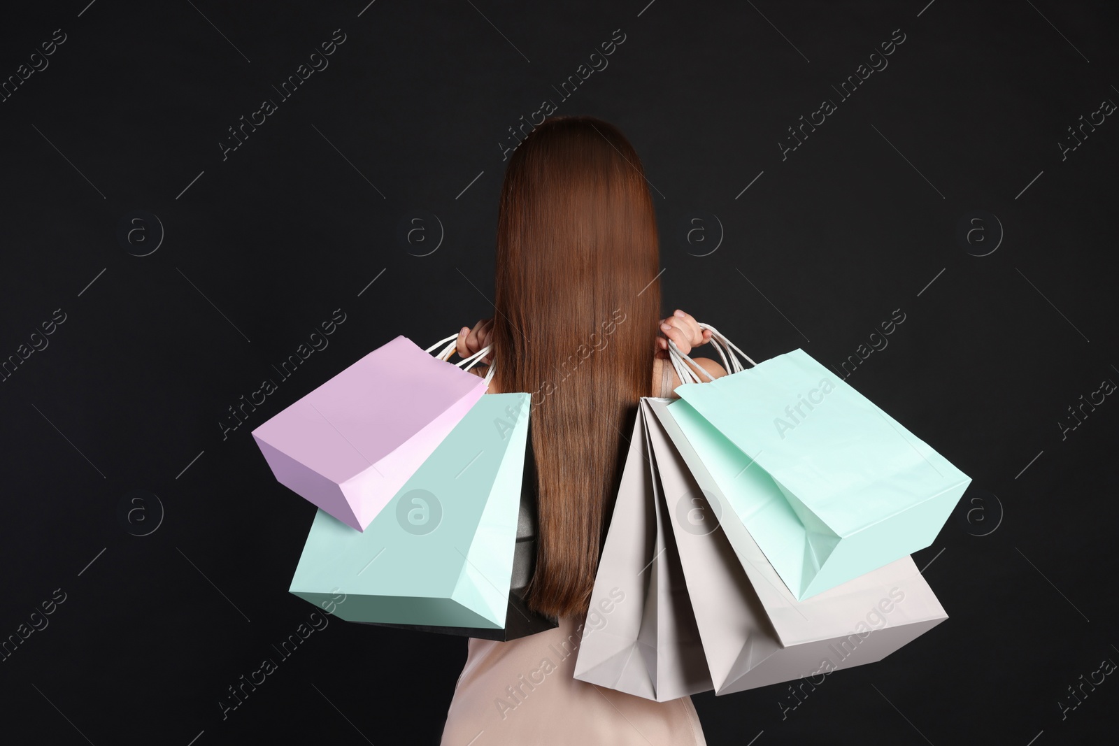 Photo of Woman with shopping bags on black background, back view. Big sale