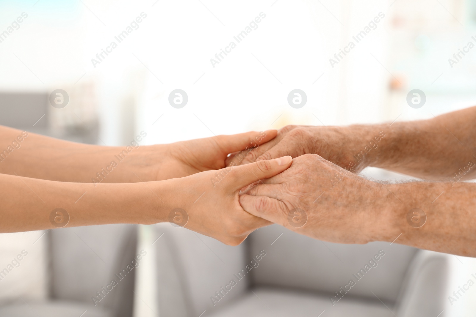 Photo of People holding hands together on blurred background, closeup. Help and elderly care concept