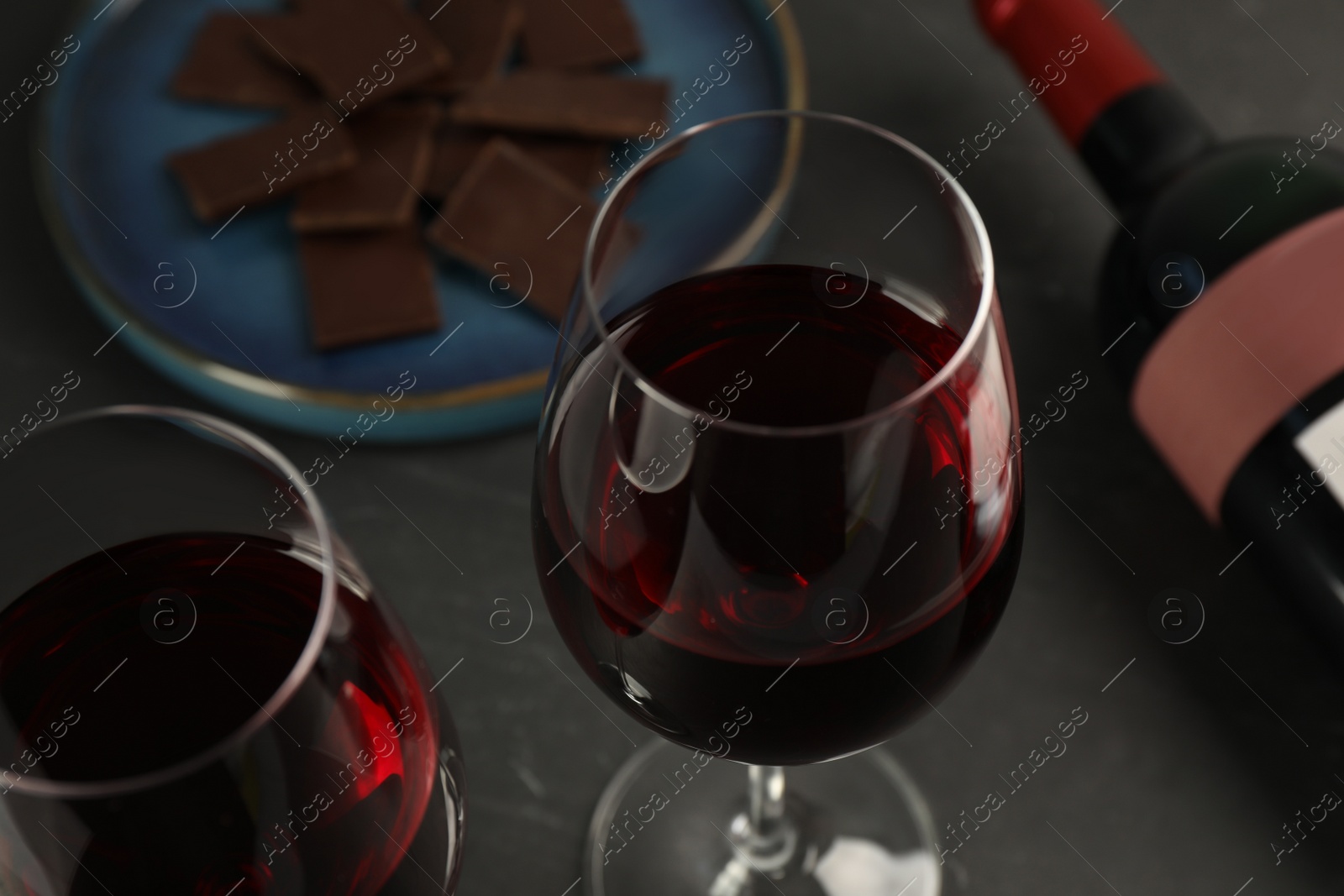 Photo of Tasty red wine and chocolate on black table, closeup