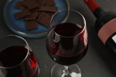 Tasty red wine and chocolate on black table, closeup