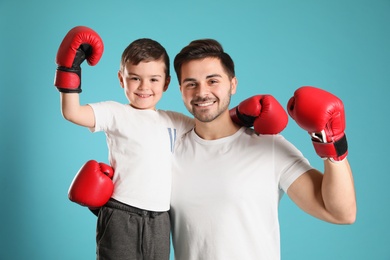 Photo of Dad and his son with boxing gloves on color background