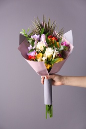 Photo of Woman with beautiful bouquet of freesia flowers on grey background