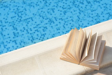 Open book on swimming pool edge during sunny day, above view. Space for text