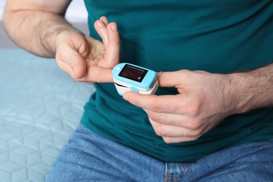 Photo of Young man checking pulse with digital medical device, closeup