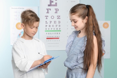 Photo of Cute little children playing doctor and patient in ophthalmologist office