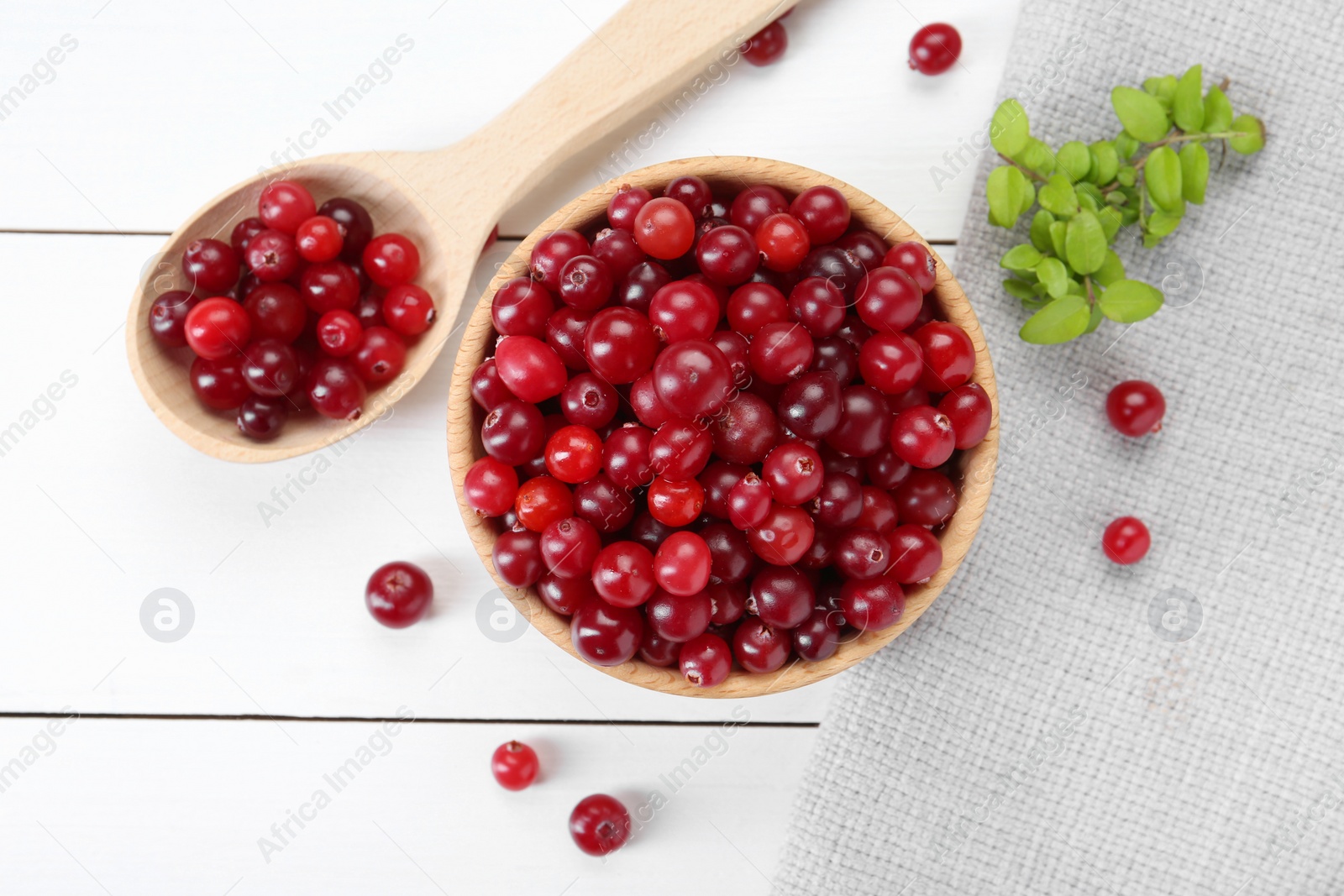 Photo of Fresh ripe cranberries and branches on white wooden table, top view