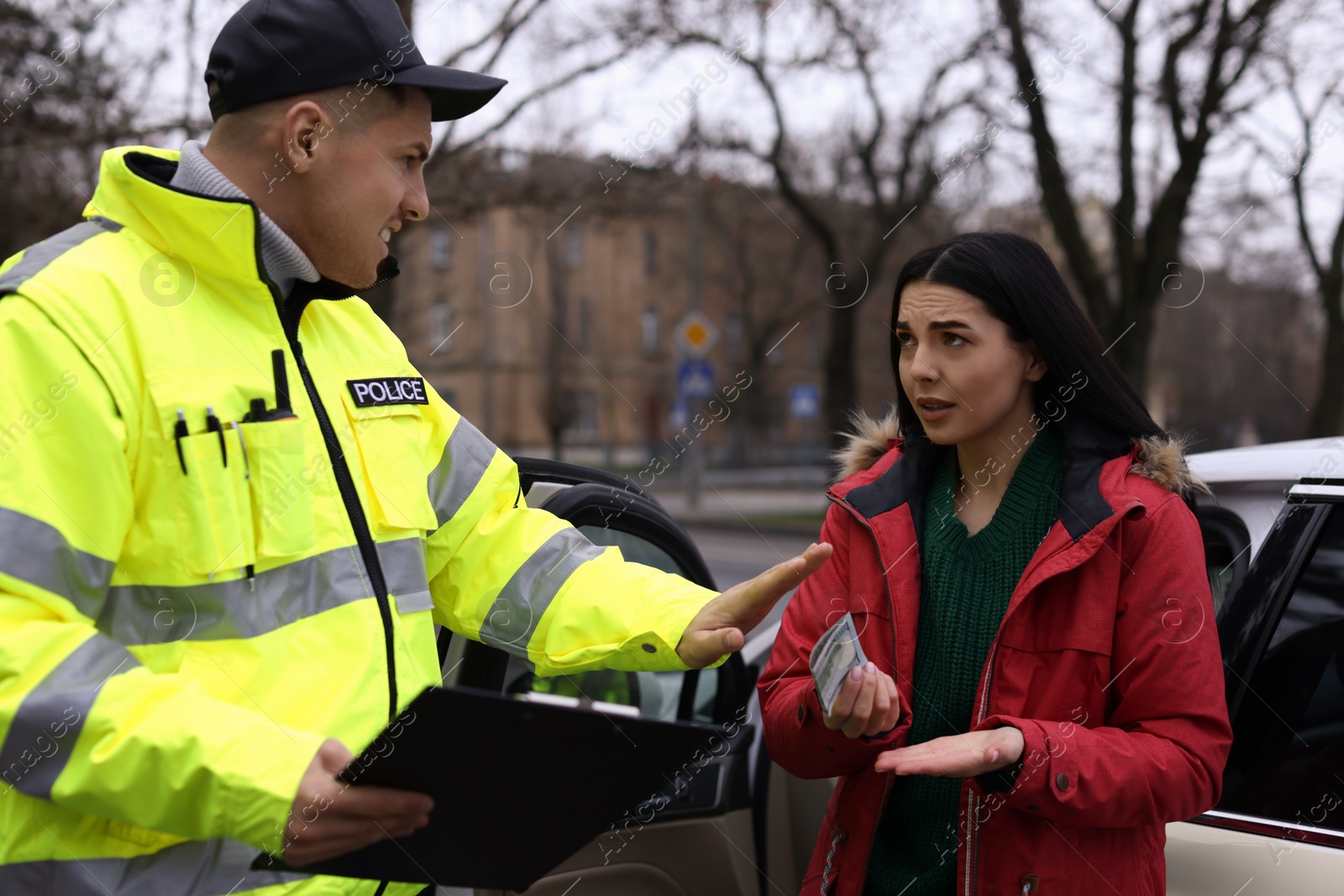 Photo of Police officer rejecting bribe near car outdoors