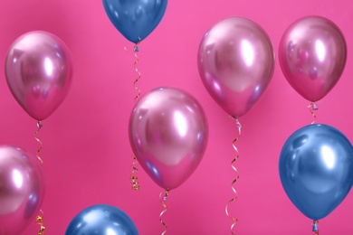 Bright balloons with ribbons on color background